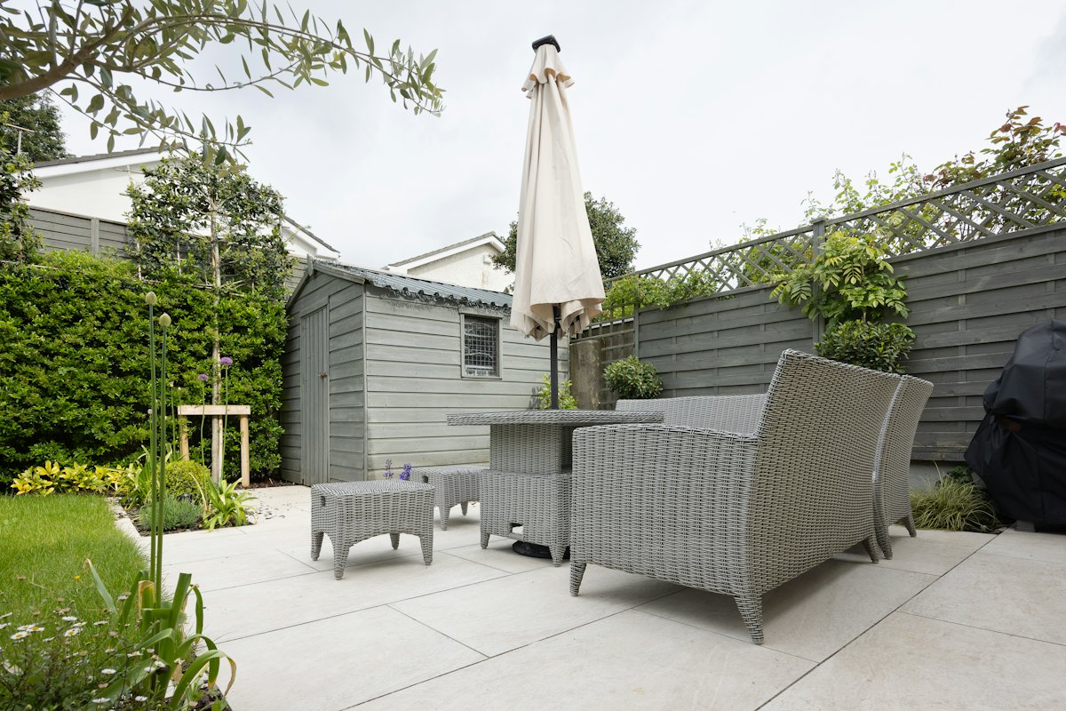 A modern paved terrace with outdoor seating and a garden shed