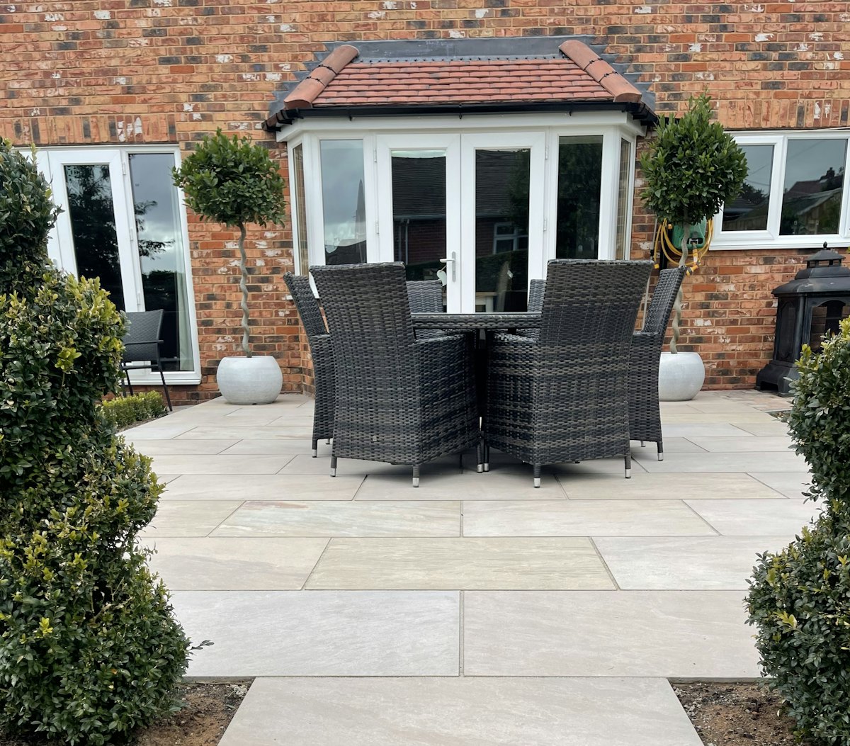 A paved patio with a dining table outside a brick house